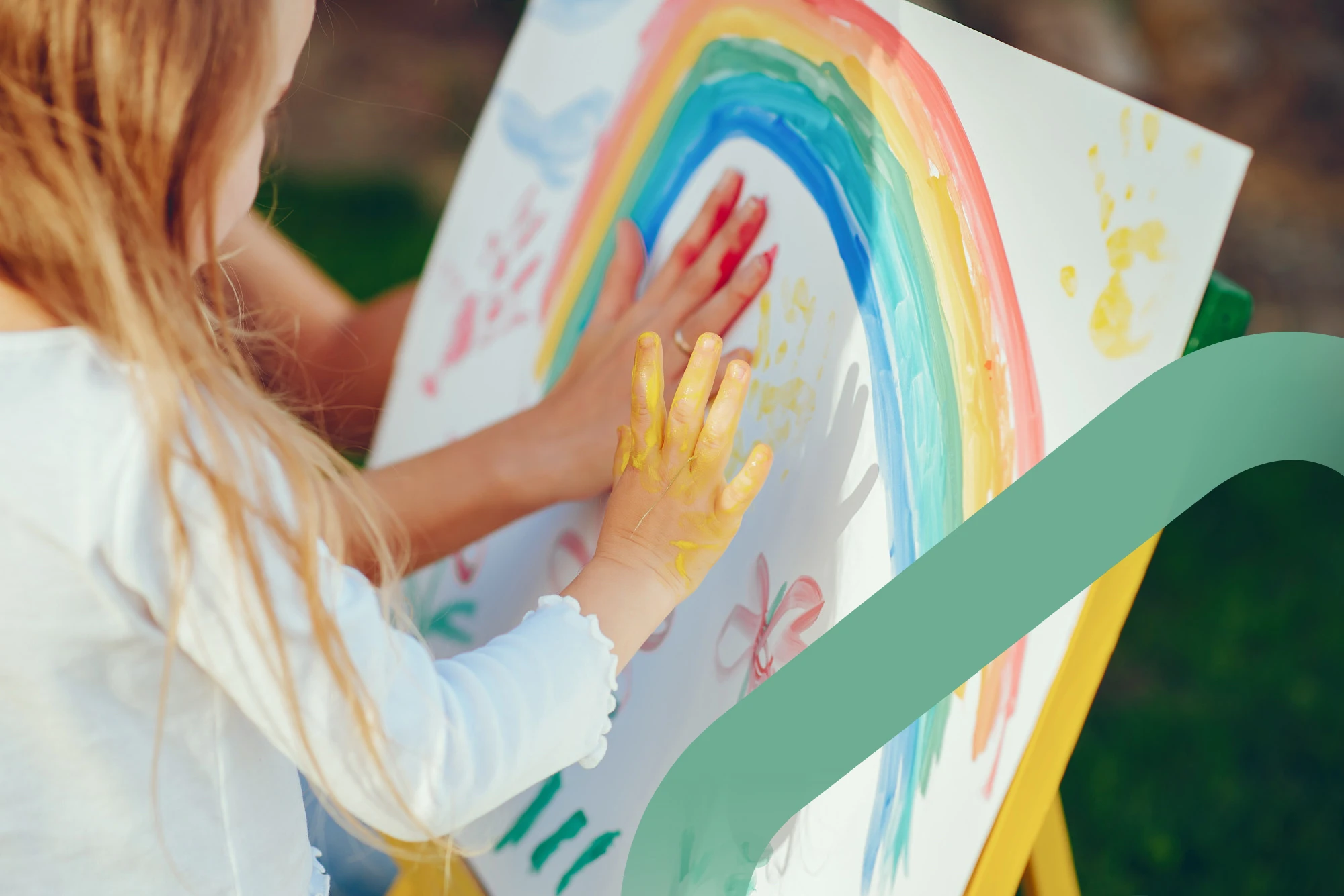 A young child finger-painting a colorful rainbow during a therapy session.